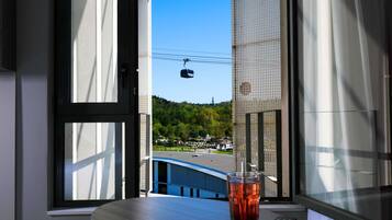 Vista por la ventana de un teleférico, un vaso de bebida roja y un control remoto sobre una mesa.