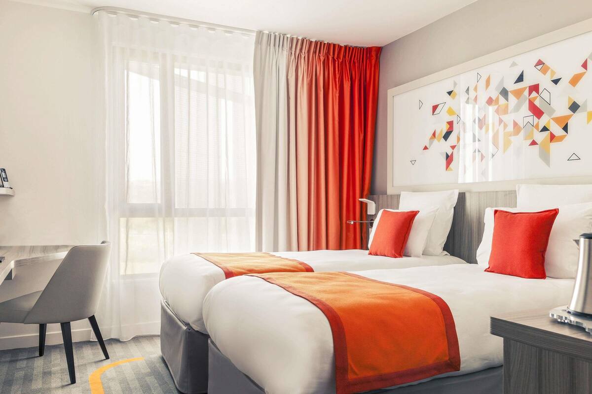 A hotel room with a bed, a desk, and a chair.