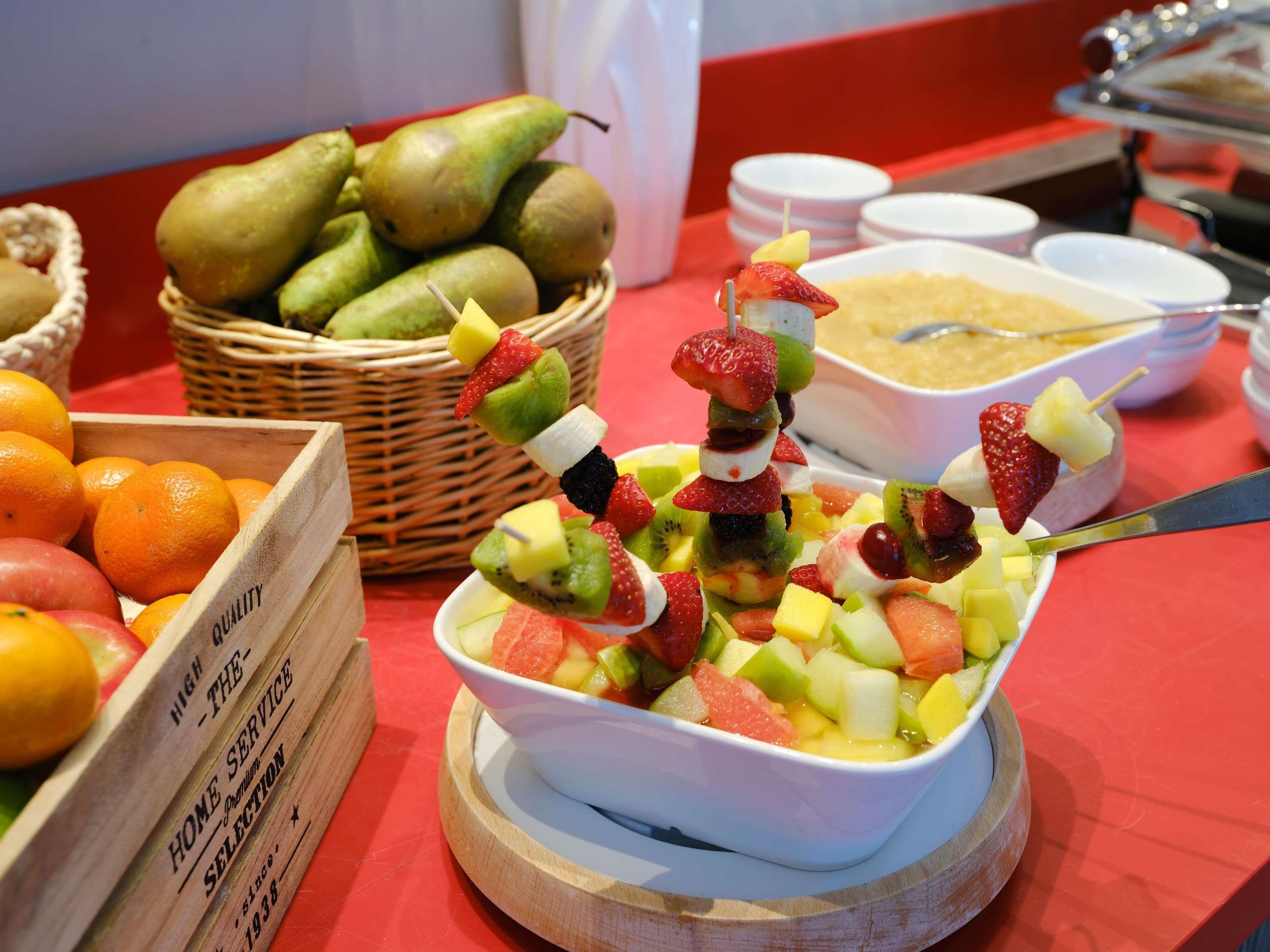 Una mesa de buffet con una variedad de frutas y un tazón de ensalada de frutas.