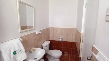 A small bathroom with a sink, two toilets, and a mirror.