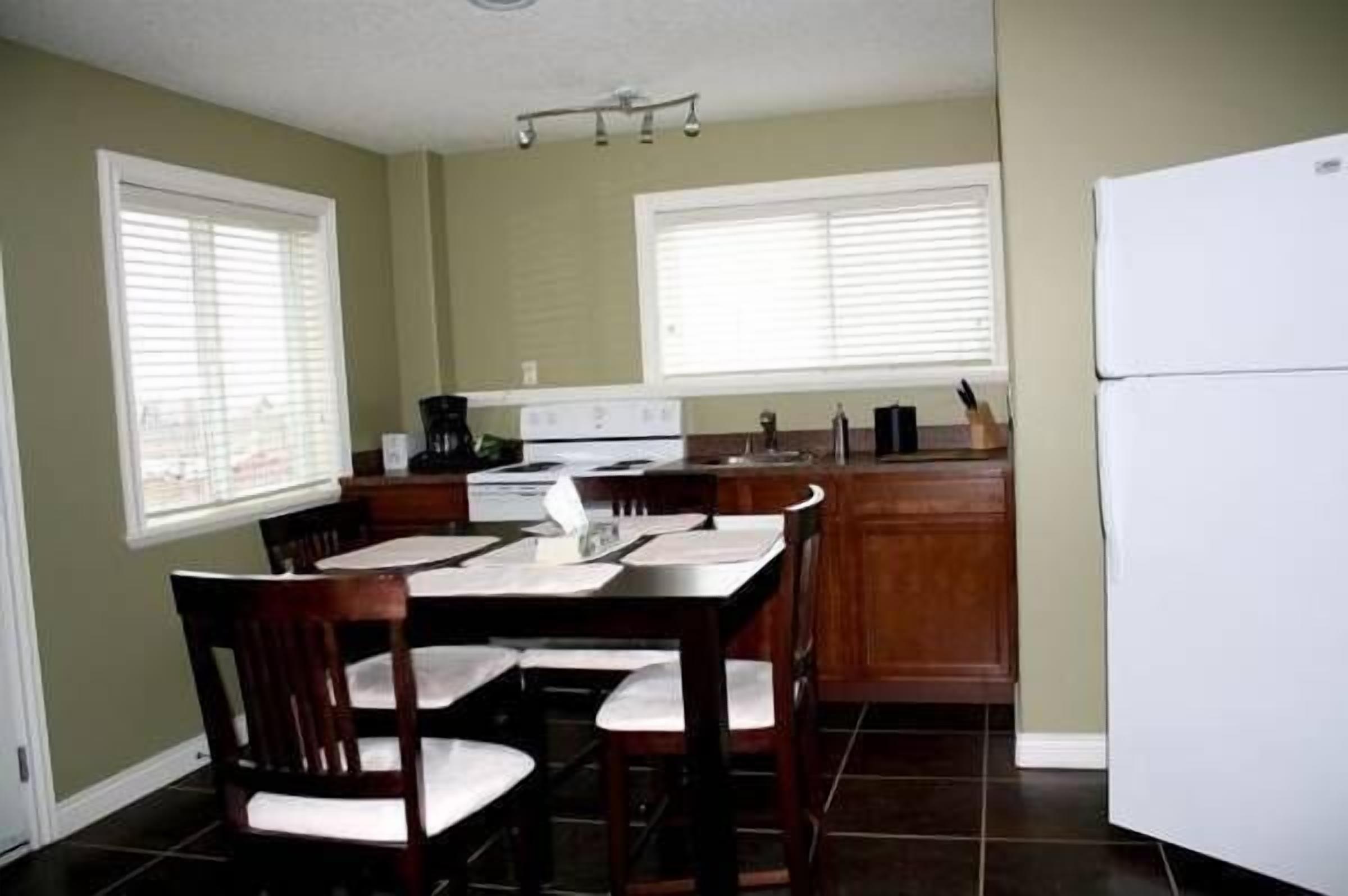 A compact kitchen with a dining table, chairs, a refrigerator, and a stove.