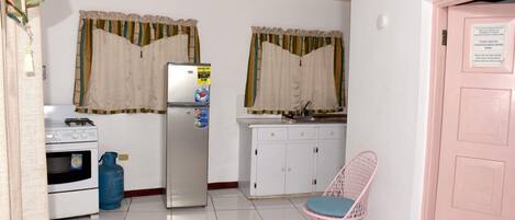Cocina compacta con refrigerador, horno y cilindro de gas.