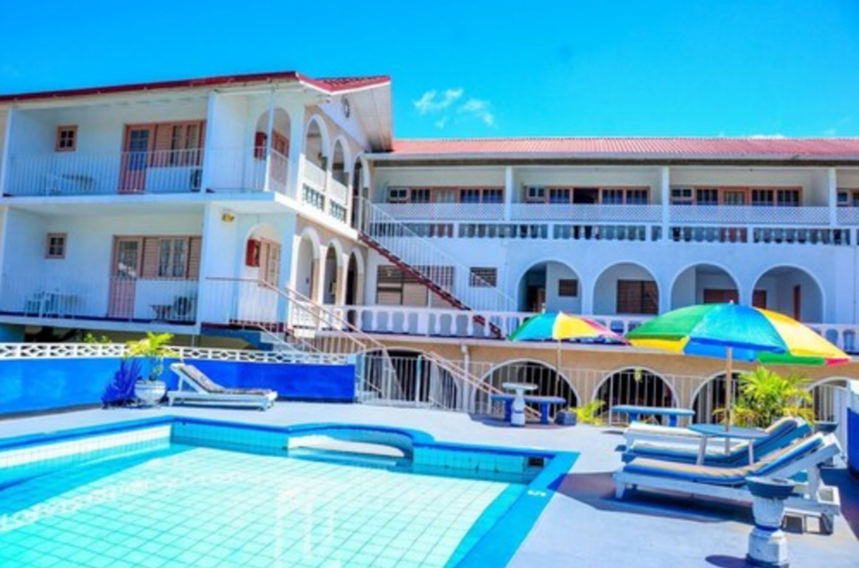 A hotel with a pool area, multiple balconies, and a covered seating area with umbrellas.