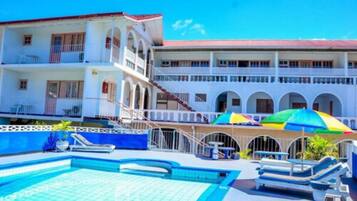 A hotel with a pool area, multiple balconies, and a covered seating area with umbrellas.