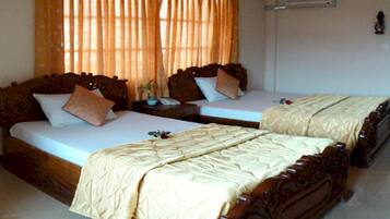 A hotel room with two double beds, a bedside table with a lamp, and a window with curtains.