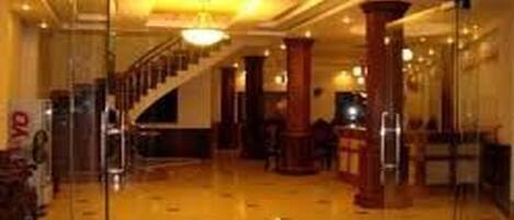A spacious lobby with a polished floor, a staircase, and a reception desk.