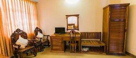 A room with a desk, two chairs, a bench, a wardrobe, and a mirror.