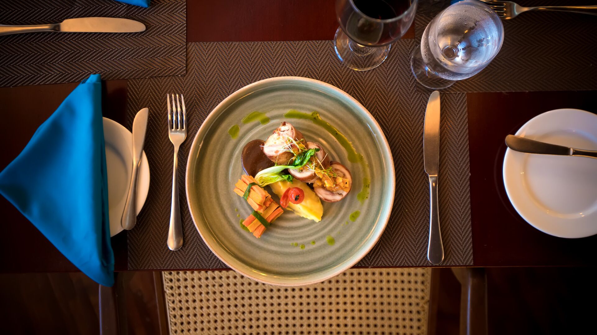 A dining table set with a plate of food, cutlery, and glasses.