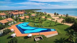 A resort with a large swimming pool, beach, and ocean view.