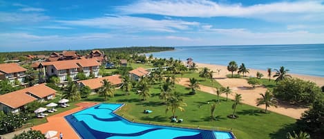 A resort with a large swimming pool, beach, and ocean view.