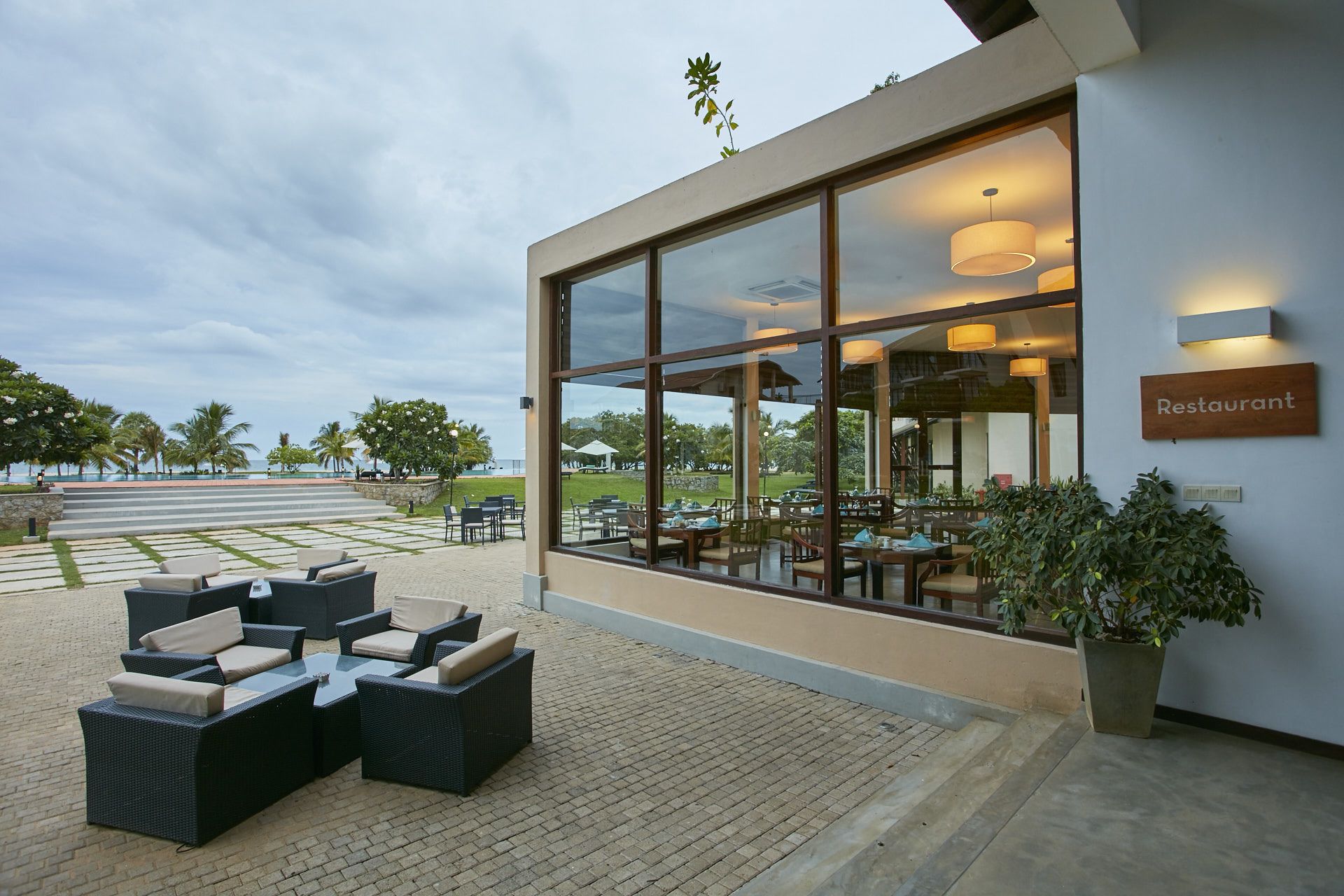 Un restaurante con terraza, grandes ventanales y vistas a la playa.