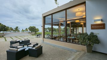 Un restaurante con terraza, grandes ventanales y vistas a la playa.