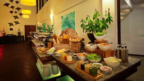 A buffet setup with various food items and a large potted plant.