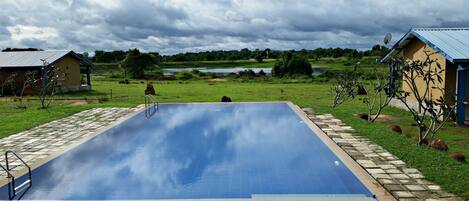 Una piscina al aire libre, una piscina con borde infinito, tumbonas