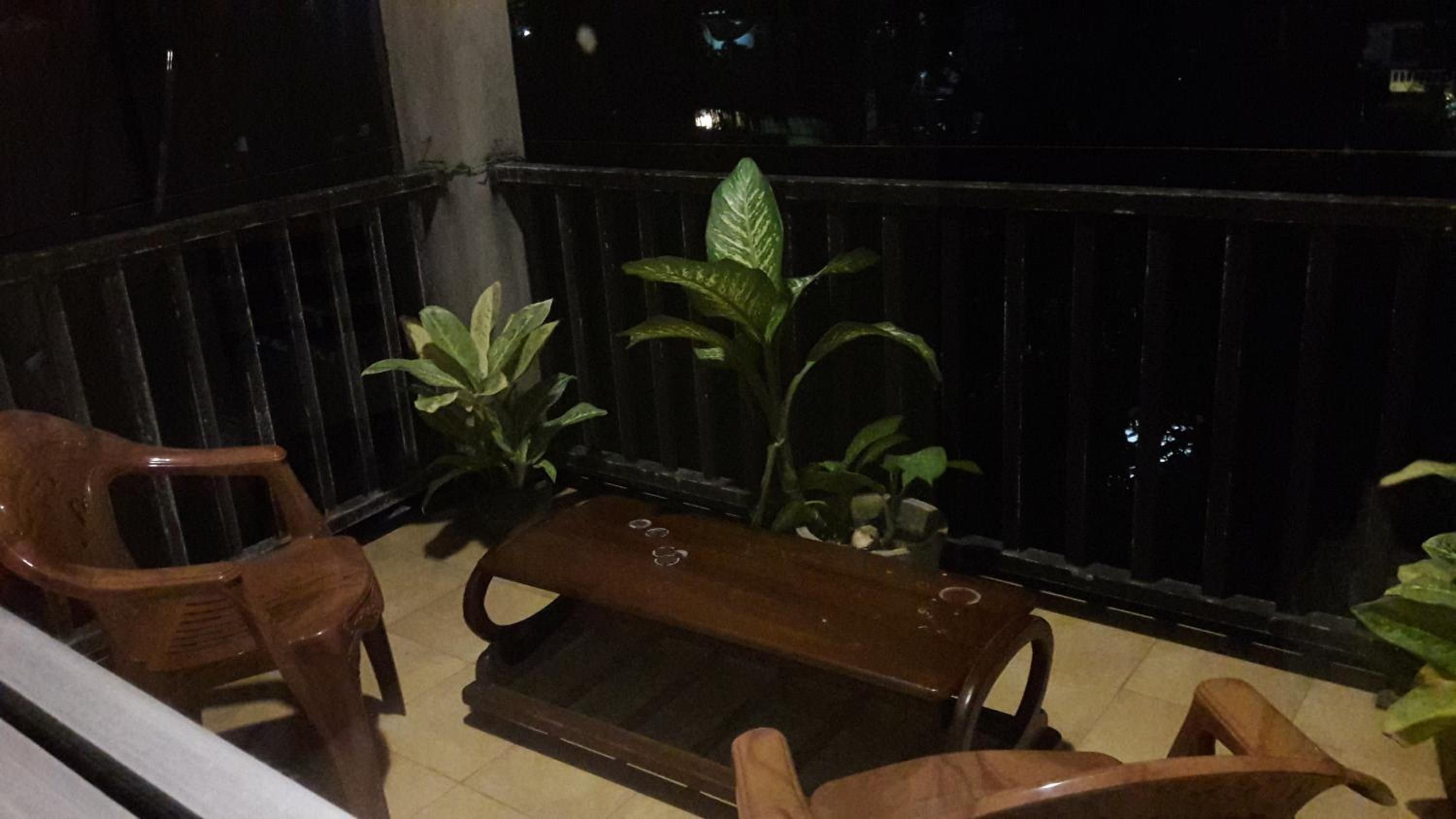 Un balcon avec un banc en bois, deux chaises et des plantes en pot.