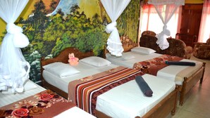 Habitación de hotel con dos camas, cada una con corredor de dosel y colcha de motivos florales.