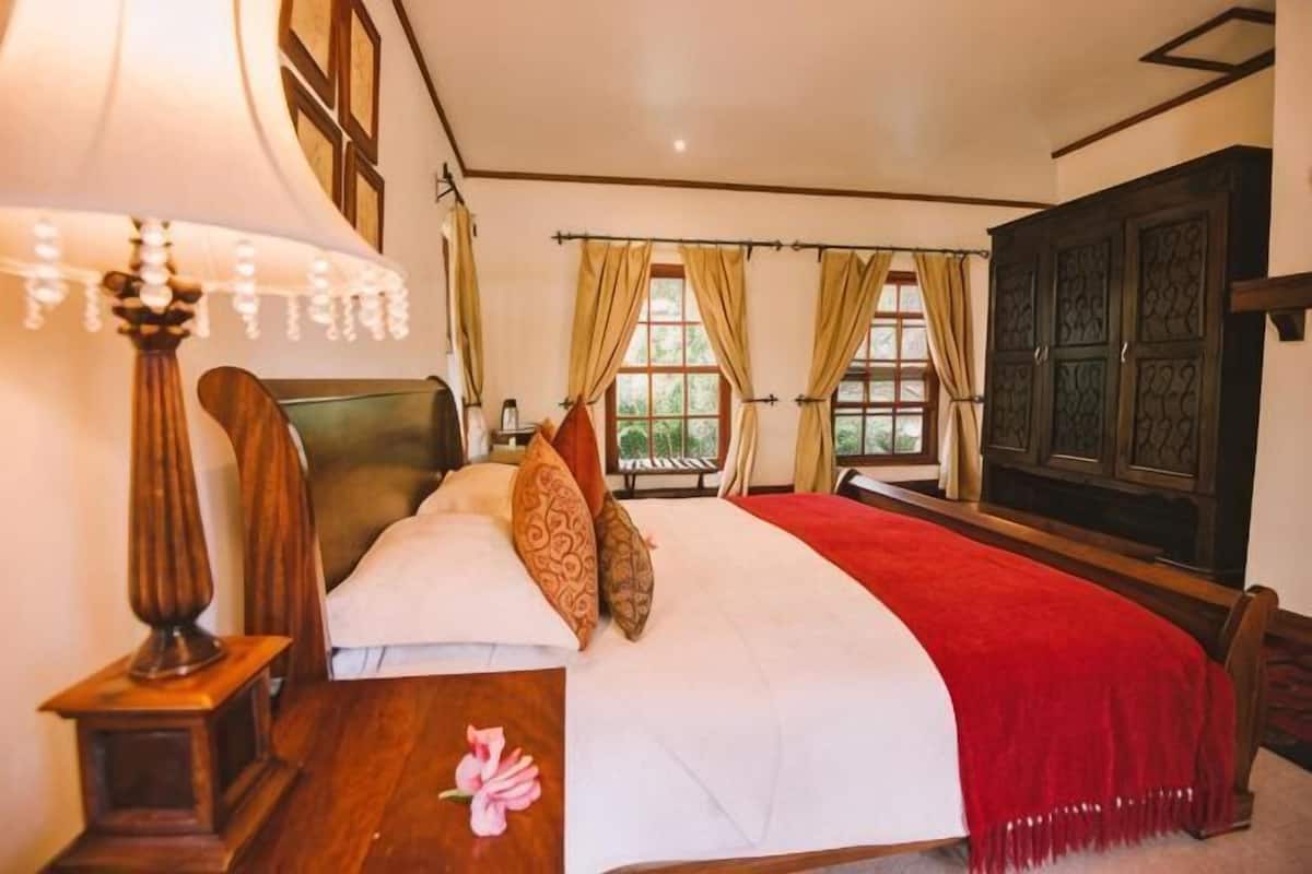 Une chambre à coucher avec un lit, une table de chevet, une lampe et une fenêtre avec des rideaux.