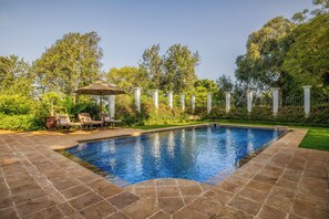 A swimming pool with a tiled deck, surrounded by a fence and lush greenery. - Elewana The Manor Ngorongoro (Karatu)