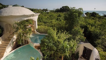 A resort with multiple swimming pools surrounded by lush greenery and a dome-shaped building.