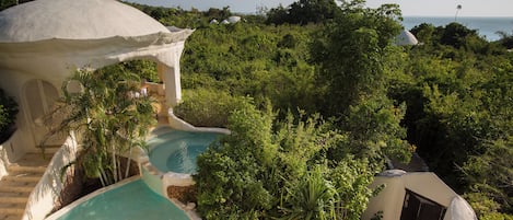 A resort with multiple swimming pools surrounded by lush greenery and a dome-shaped building.