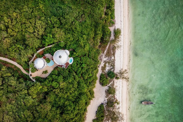 An aerial view of a resort with multiple structures, a beach, and a boat.