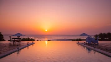 Een buitenzwembad, een infinity pool, parasols voor strand/zwembad