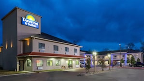 A Days Inn & Suites building with a sign, a parking lot, and a small garden area. - Days Inn & Suites by Wyndham Madisonville (Madisonville)