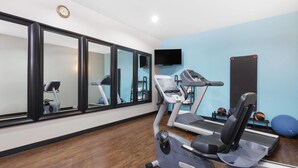 A gym with treadmills, exercise balls, and a large mirror. - Days Inn & Suites by Wyndham Madisonville (Madisonville)