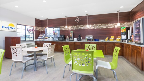 A breakfast area with a Daybreak sign, a coffee machine, and a refrigerator with beverages. - Days Inn & Suites by Wyndham Madisonville (Madisonville)