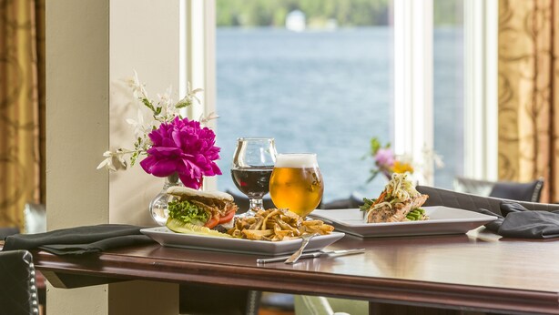 A dining table with a meal, a glass of beer, and a view of a lake. - Lake Morey Resort (Fairlee)