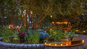 A garden with a stone wall, a wooden bench, and a gazebo. - Lake Morey Resort (Fairlee)