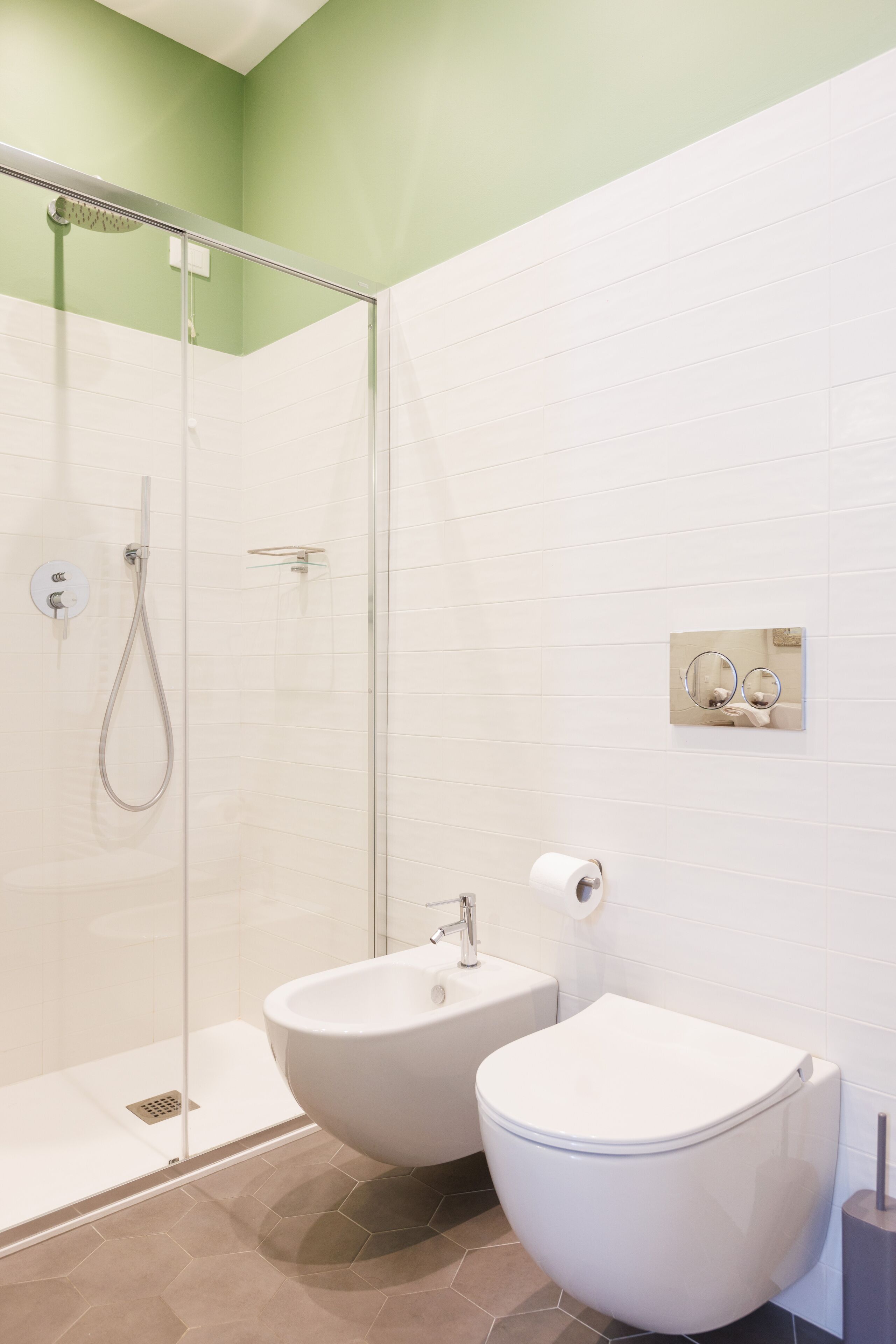 A modern bathroom with a glass-enclosed shower, a bidet, and a toilet.