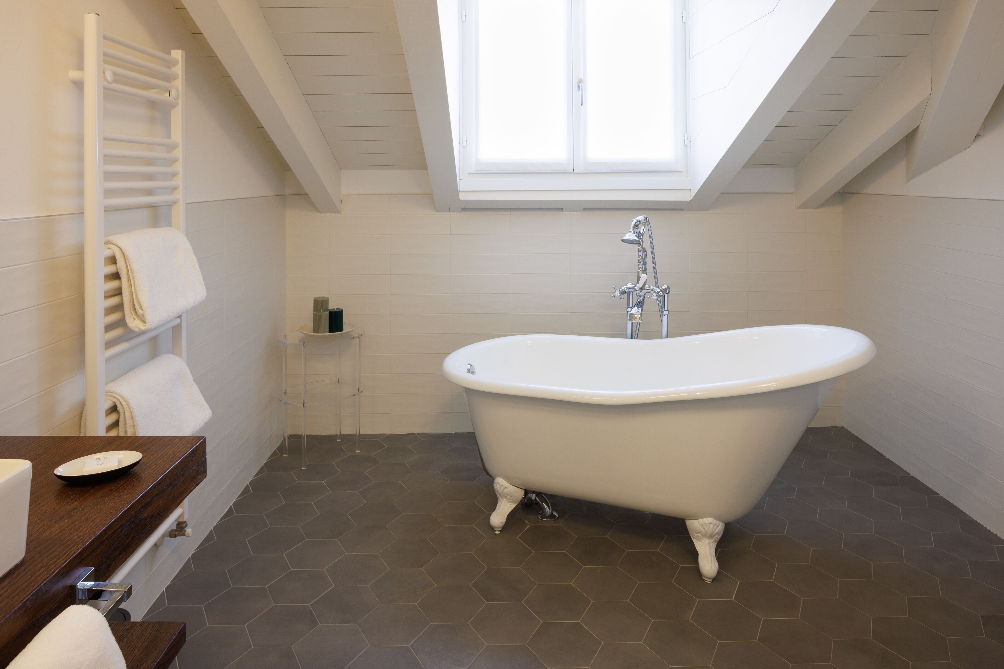A modern bathroom with a freestanding bathtub, a towel rack, and a window above the tub.