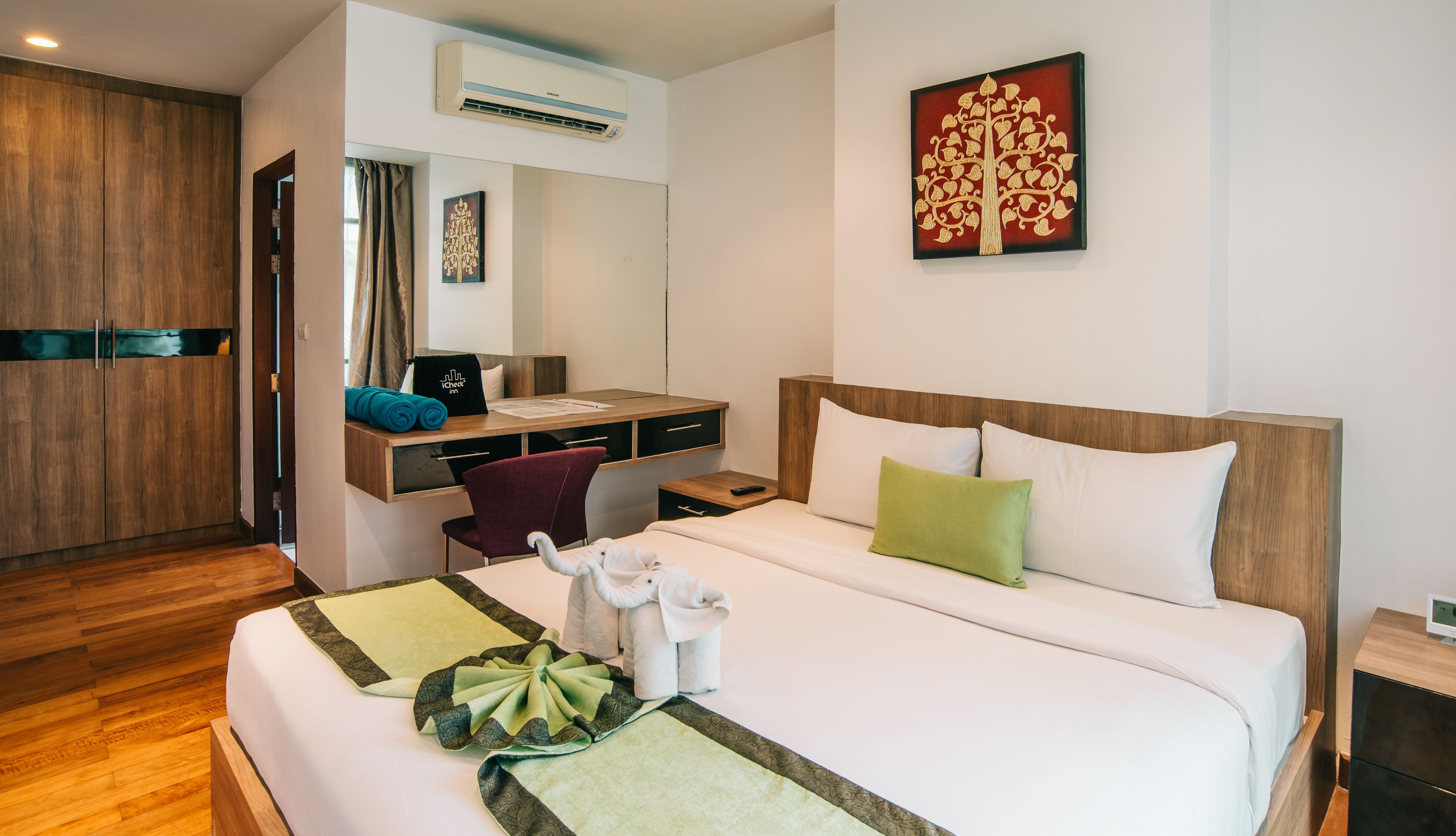 Een hotelkamer met een bed, bureau, stoel en een airconditioning.