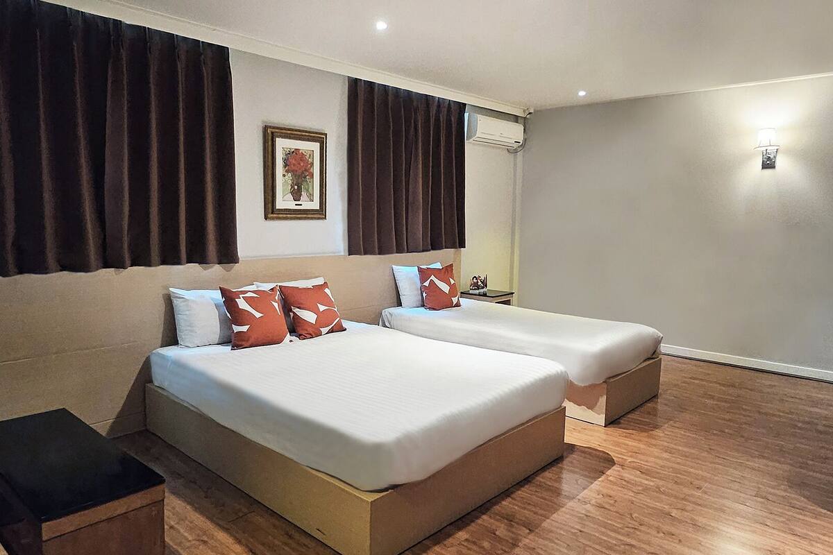 A hotel room with two beds, a small table, and a nightstand.