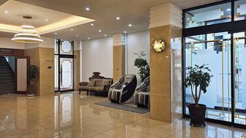 A modern lobby with a reception desk, seating area, and massage chairs.