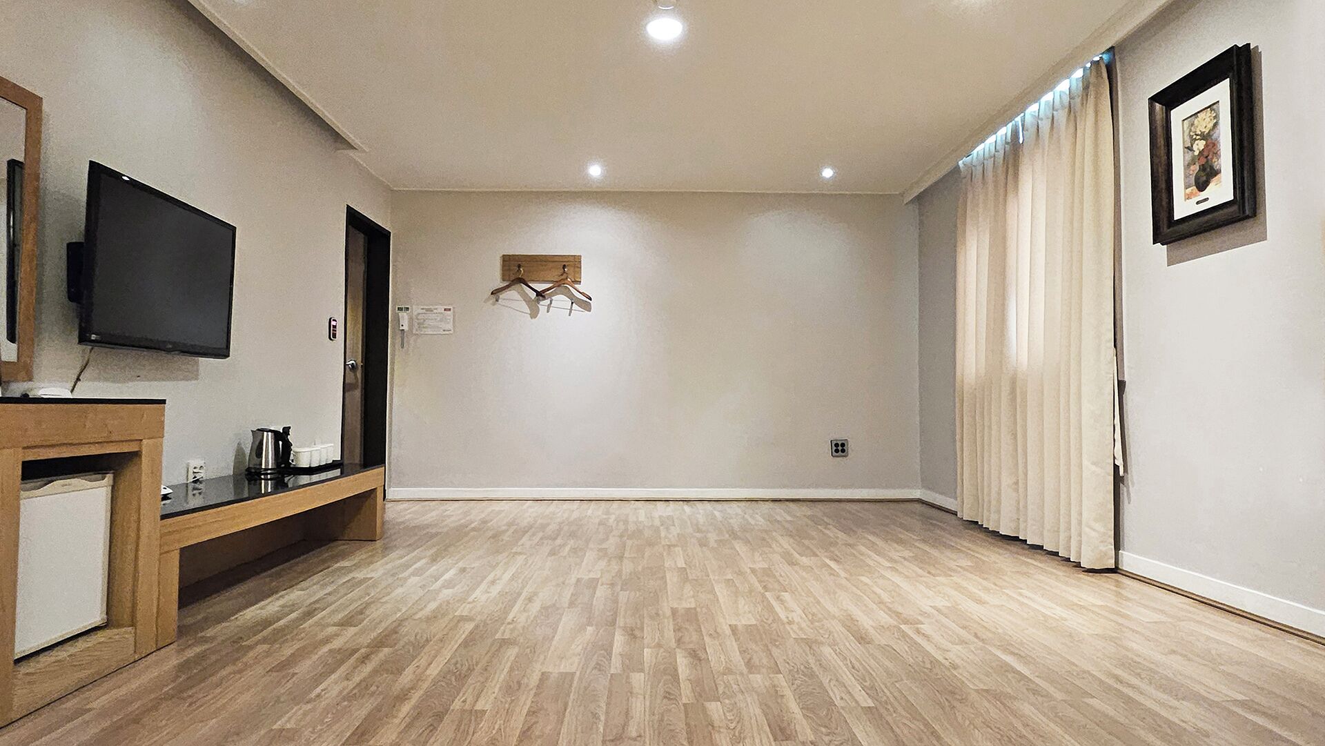 Ein geräumiges Zimmer mit einem Flachbildfernseher, einem Holzkonsolentisch und einem Kleiderständer.