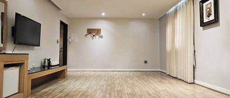 Una habitación amplia con televisión de pantalla plana, una consola de madera y un perchero.