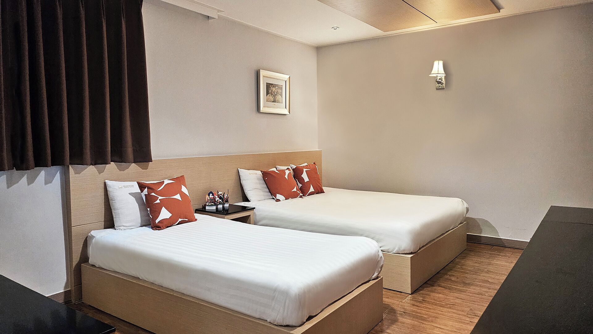 Una habitación de hotel con dos camas, una mesita de noche, una lámpara y un cuadro en la pared.