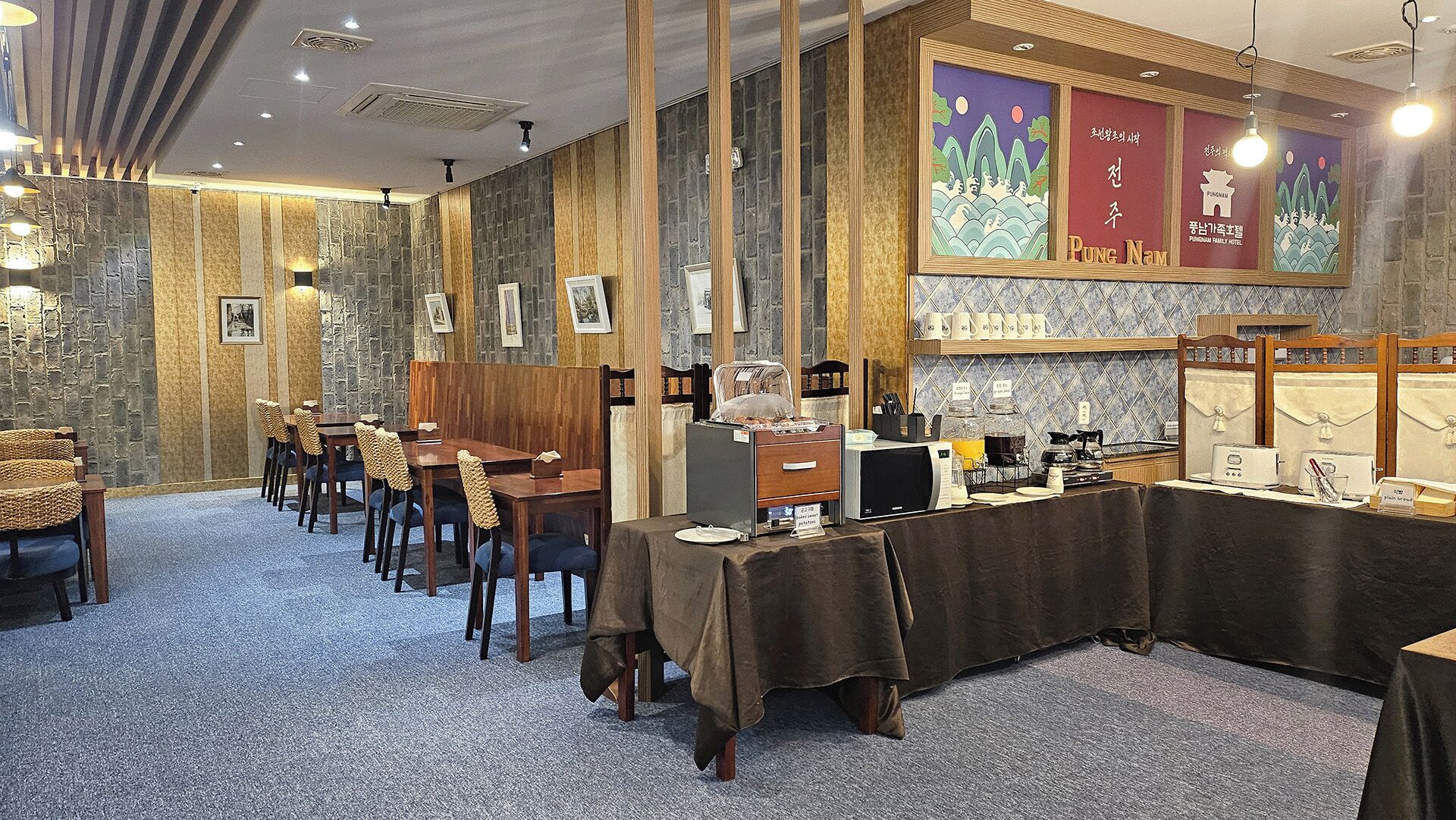 Un restaurante con una barra larga, sillas de madera y un fondo de pared de piedra.
