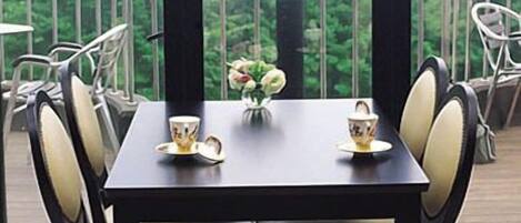 A dining table with four chairs, a vase with flowers, and a bottle on the table.