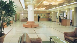 Un hall d’entrée spacieux comprenant un comptoir d’accueil, un espace salon et une grande colonne.