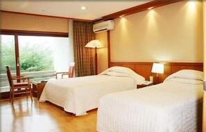 Une chambre d’hôtel avec deux lits, une chaise et une fenêtre avec des rideaux.