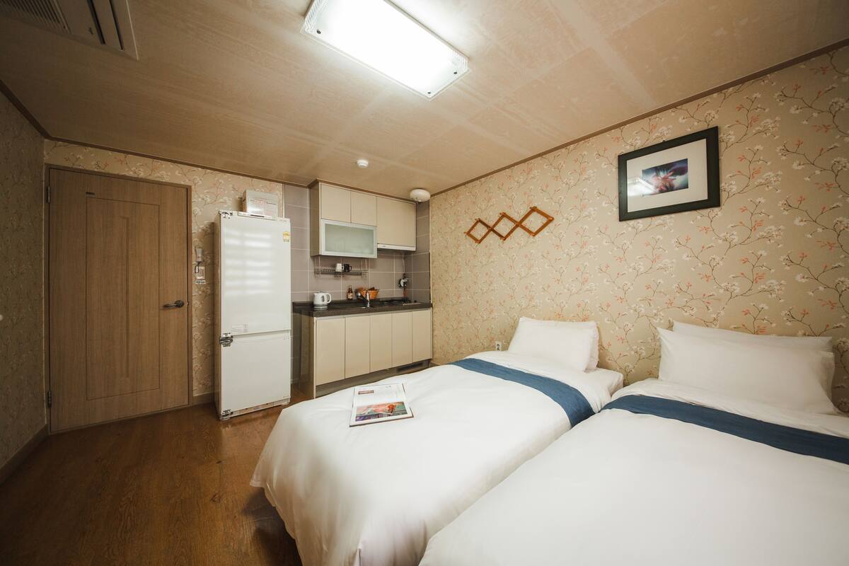 A hotel room with a bed, a small kitchenette, and a wooden door.
