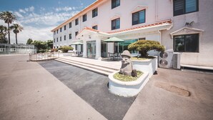 Un hotel con fachada blanca, varias ventanas y un área de estar exterior cubierta con sombrillas.