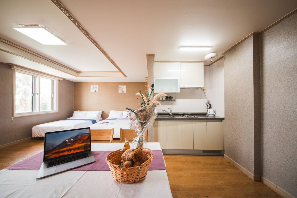 A bedroom with a bed, a laptop, and a decorative vase on a table.