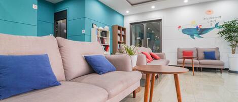 A modern waiting area with a sofa, a small table, and a bookshelf.