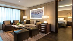 A modern hotel room with a sofa, two armchairs, a coffee table, a side table with lamps, a bed, and a large artwork on the wall. - Teda, Tianjin-marriott Executive Apartments (Tianjin)