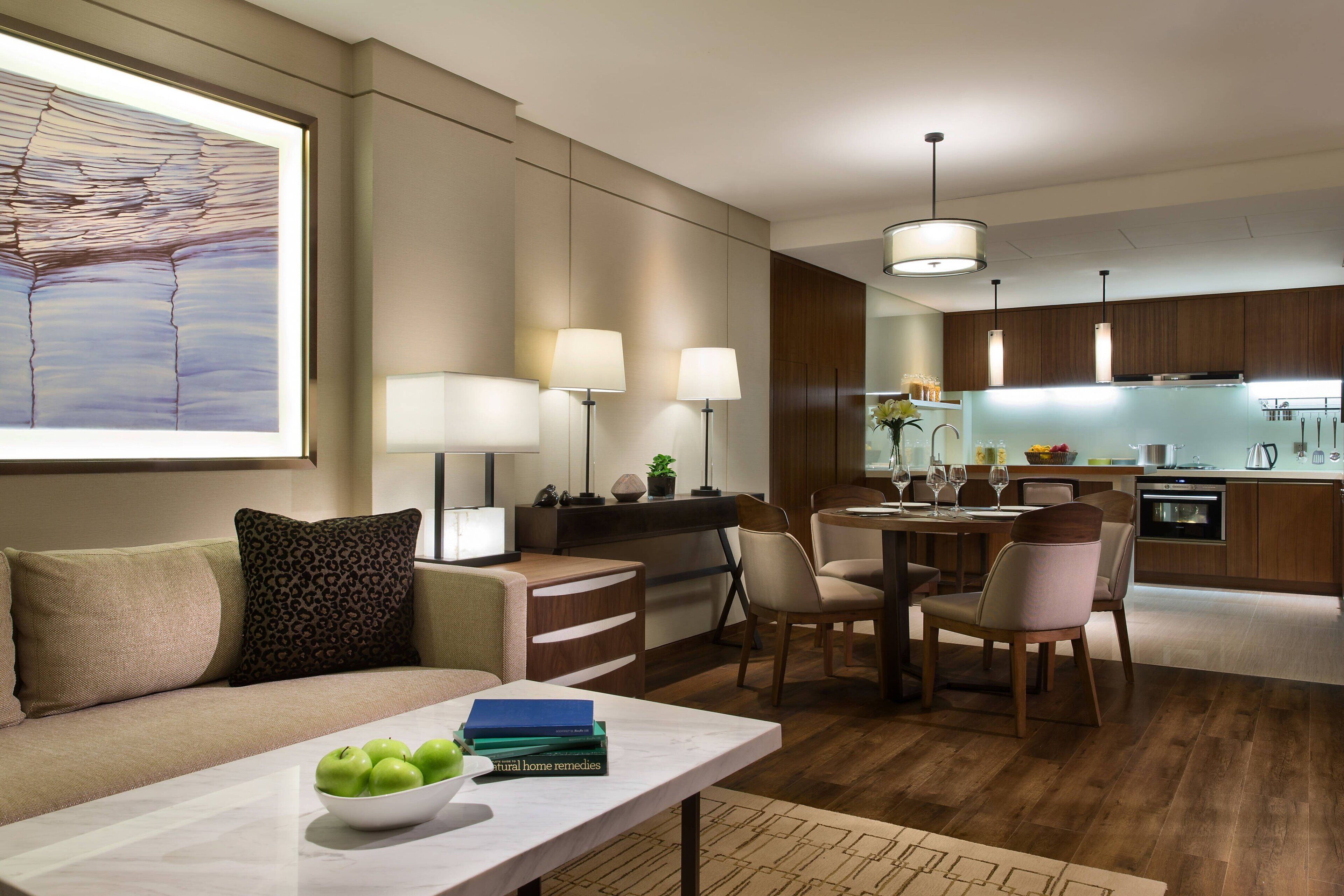 Un salon moderne avec un canapé, une table basse sur laquelle sont posées des pommes, et un coin repas comprenant des chaises et une table.