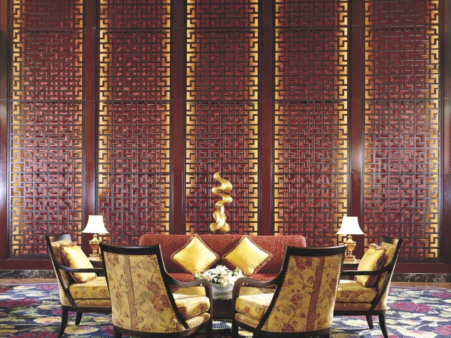 A room with a round table, four chairs, and a decorative wall with vertical panels.